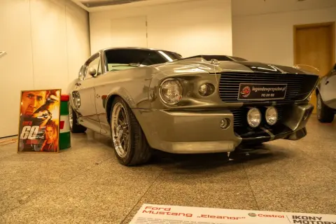 Szary Ford Mustang „Eleanor” z filmu „60 sekund” obok plakatu z Nicolasem Cage'em.