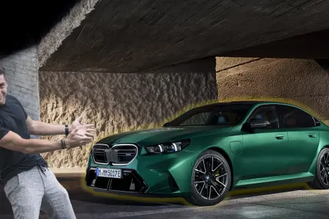 Mężczyzna z entuzjazmem prezentuje lśniące, zielone bmw g90 pod betonowym zadaszeniem.