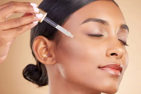 Delikatna aplikacja serum z kwasem salicylowym i retinolem na twarz. Skóra staje się gładka i promienna.
