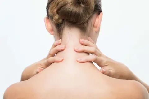 Mains massant une nuque raide, signe de stress.