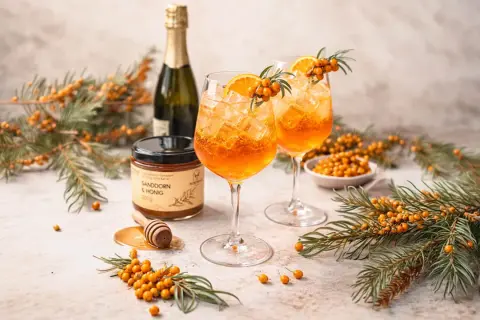 Erfrischende Sanddorn-Cocktails mit Orange und Eis, daneben Sanddorn & Honig. So schmeckt Sanddorn: fruchtig-herb und belebend.