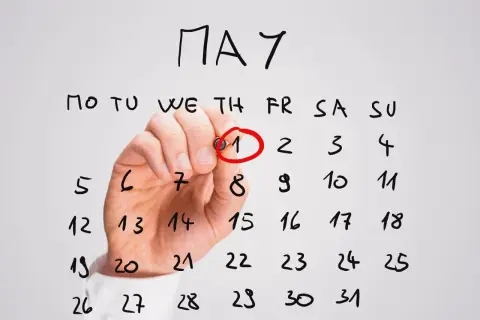Ręka zaznacza czerwonym markerem 1 maja na kalendarzu. Planujesz dpd przekierowanie paczki?