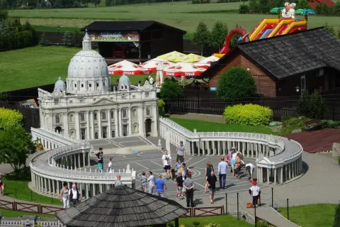 Miniaturowy park z modelem Bazyliki św. Piotra i placem Berniniego. W tle zjeżdżalnia i budynki. Sprawdź inwałd park cennik.