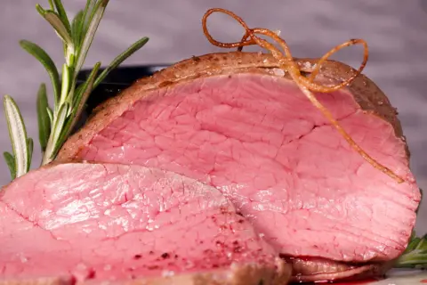Saftiges Rinderfilet im Backofen, perfekt rosa gebraten, mit Rosmarin und einer dekorativen Schnur aus Bratensaft.