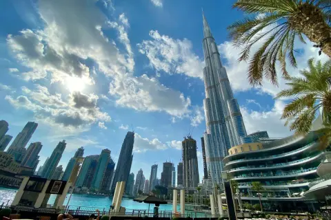 Burj Khalifa i inne drapacze chmur w Dubaju. Słońce przebija się przez chmury. Warto zabrać do Dubaju okulary przeciwsłoneczne i lekki ubiór.