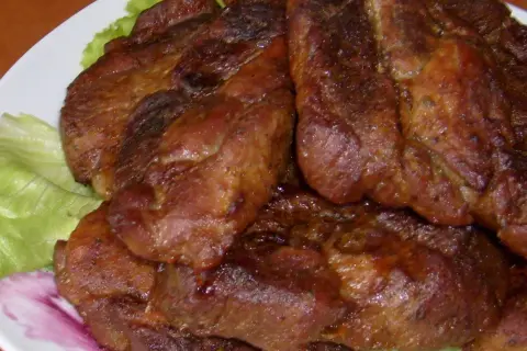 Soczysta karkówka pieczona na talerzu z sałatą.