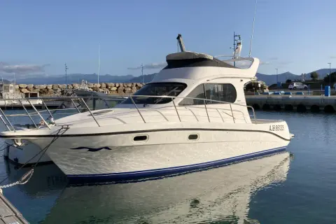 Yacht Intermare 30 ormeggiato in porto, con riflessi sull'acqua calma. Montagne sullo sfondo.