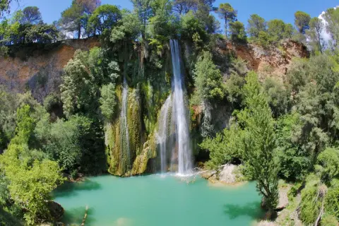 La cascade de Sillans, un spectacle naturel impressionnant, se jette dans un bassin d'eau turquoise entouré de verdure luxuriante.
