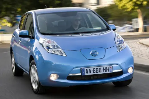 Un coche azul Nissan Leaf, uno de los coches mas fiables de segunda mano, circula por una carretera.