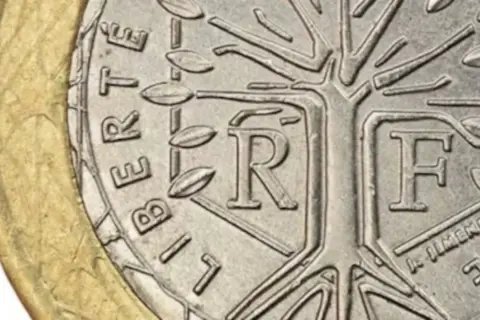 Detalle de una moneda de la República Francesa con un árbol estilizado y las letras "R" y "F".