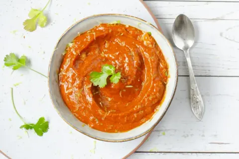 Un tazón de cremosa salsa chipotle, adornado con cilantro fresco y ralladura de lima, listo para acompañar tus platillos.