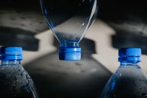 Bouteilles d'eau en plastique avec bouchons bleus. L'eau de Mont Roucous, une source d'eau naturelle, peut présenter un danger si elle est mal conservée.