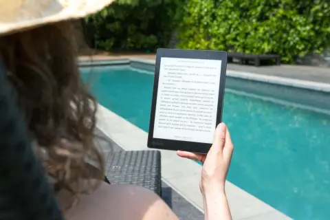 Une personne lit un livre électronique Kobo au bord d'une piscine, profitant du soleil. Un excellent choix pour un epub reader sur Ubuntu.