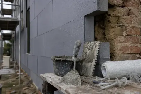 Attrezzi da cantiere e materiali per cappotto termico. Si intravedono mattoni a vista, forse un limite di questo sistema.