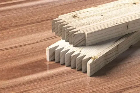 Dos tablas de madera con cortes en forma de dientes de sierra listas para unir tablero.