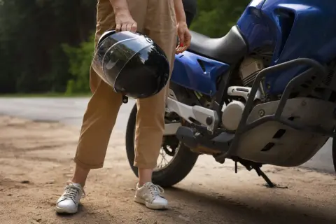 Osoba trzyma kask obok niebieskiego motocykla. Zastanawiasz się, czy można holować motocykl?