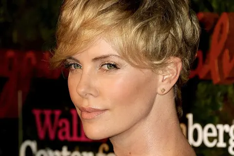 Charlize Theron w fryzurze pixie, która dodaje objętości cienkim włosom, z subtelnym makijażem i złotą biżuterią.