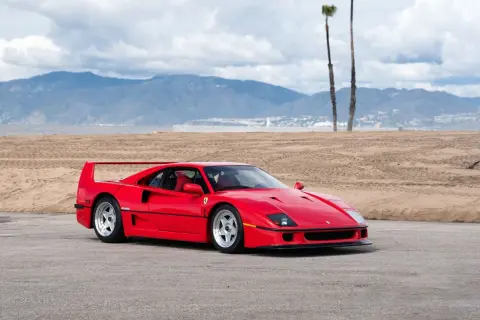 Czerwone Ferrari f40 na tle plaży i gór. Ikona motoryzacji gotowa do jazdy.