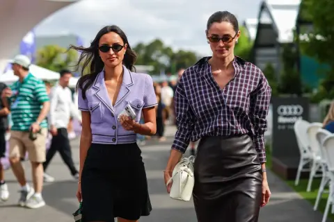 Rebecca Donaldson y su amiga pasean con estilo. Una lleva un blazer lila y falda negra, la otra, camisa a cuadros y falda de cuero.