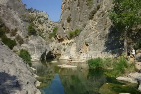 Un cañón con un río de aguas cristalinas y vegetación exuberante, ideal para disfrutar de los warmwaterbronnen in Spanje.