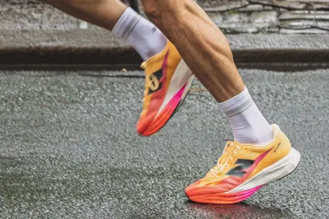 Biegacz w kolorowych butach do biegania, idealnych na treningi hiit, pokonuje mokrą nawierzchnię.