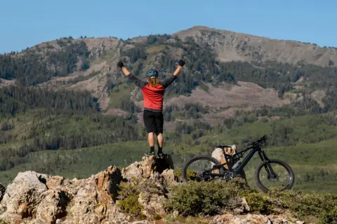 Ciclista celebra cima de montaña, listo para un camino de Santiago en bici con niños.