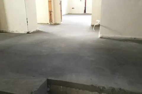 Surowy, betonowy jastrych co to? To podłoga gotowa na wykończenie. Widać fragmenty ścian i instalacji.
