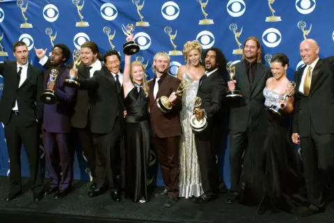 Die Besetzung von Lost feiert Emmy-Gewinne. Die Schauspieler posieren mit ihren Trophäen vor einem blauen Banner mit dem CBS-Logo.