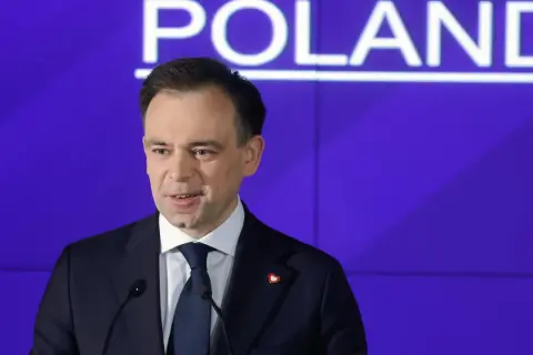 Mężczyzna w garniturze przemawia na tle napisu "POLAND". Dyskutuje o przyszłości cyfrowej gospodarki i potencjalnym podatku cyfrowym.