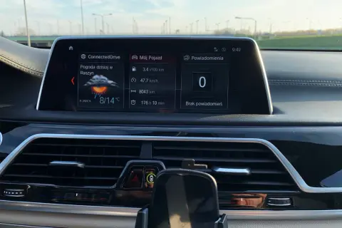 Wnętrze BMW hybryda: ekran z pogodą w Raszynie (8/14°C), spalaniem 3.4l/100km i przebiegiem 8043km.