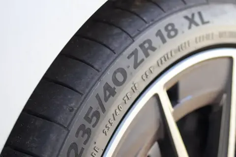 Gros plan sur un pneu de voiture avec l'inscription "235/40 ZR 18 XL", indiquant une capacité de charge renforcée pour une conduite sportive.