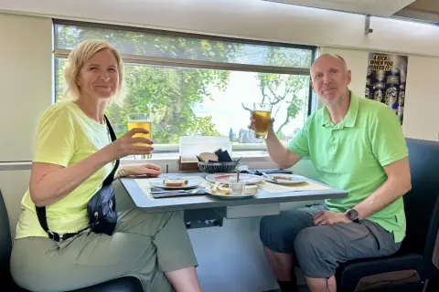 Ett par skålar med öl på ett tåg till München. De njuter av en måltid med bröd, ost och charkuterier medan landskapet susar förbi utanför fönstret.