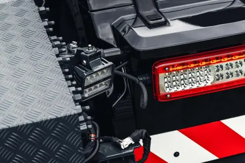 Feu arrière LED d'un véhicule tout-terrain, avec une bande réfléchissante rouge et blanche. Un projecteur auxiliaire est monté à proximité, conforme à la norme IP63.