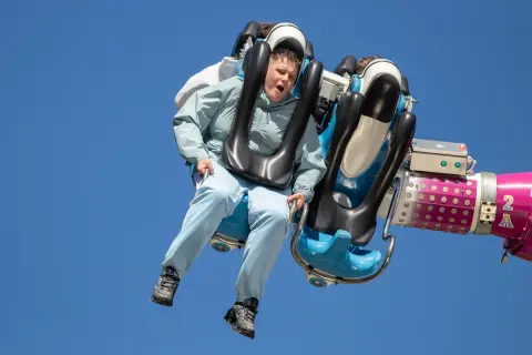 Junge auf einer wilden Fahrt auf der Kirmes Ründeroth, der Wind weht durch sein Haar.