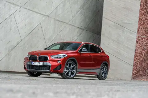 Czerwone BMW X2 na tle nowoczesnej architektury. Wiele osób szuka bmw x2 opinie przed zakupem.