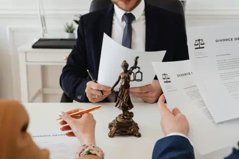 Prawnik analizuje dokumenty rozwodowe, obok figurki Temidy. Zapewnienie sprawiedliwego podziału majątku.