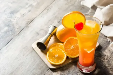 Kolorowy drink Tequila Sunrise, pomarańcze i miarka barmańska. Idealny przepis na lato!