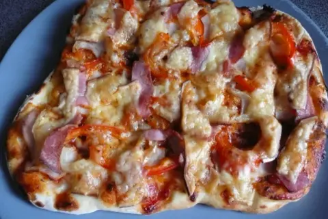 Pyszna pizza z szynką, papryką i cebulą, zapieczona pod ciągnącym się serem. Idealna na szybki obiad.