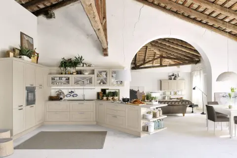 Jasna kuchnia shabby chic z drewnianymi belkami na suficie, wyspą i otwartą przestrzenią z sofą.