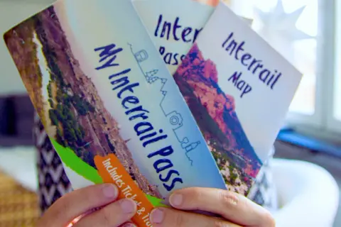 Ręce trzymają broszurę "My Interrail Pass" i mapę. To świetny sposób na podróżowanie po Europie, jeśli zastanawiasz się interrail co to.
