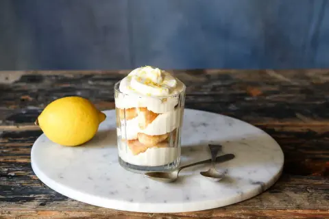 Un délicieux tiramisu aux agrumes, servi dans un verre, avec un citron frais à côté.