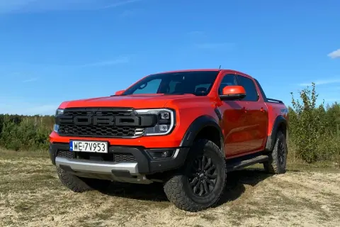 Pomarańczowy Ford Raptor na tle nieba i lasu. Zastanawiasz się nad jego **spalaniem**?