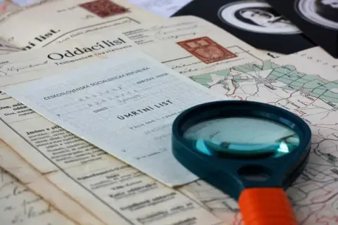 Loupe pour retrouver un acte de décès. Documents anciens, carte et loupe suggèrent une recherche généalogique.