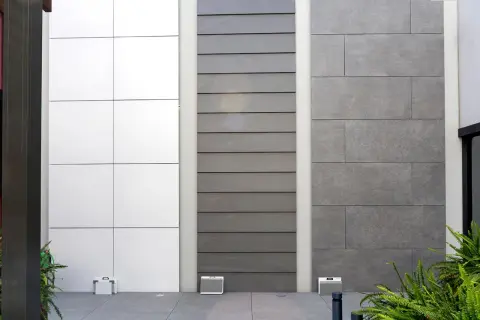 Muestras de paredes porcelanico para fachadas exteriores: paneles blancos, listones grises y baldosas de gran formato en gris oscuro.