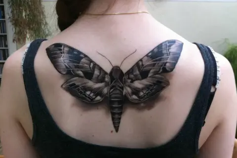 Realistyczny tatuaż ćmy na plecach. Ćma symbolizuje transformację, noc i tajemnicę.