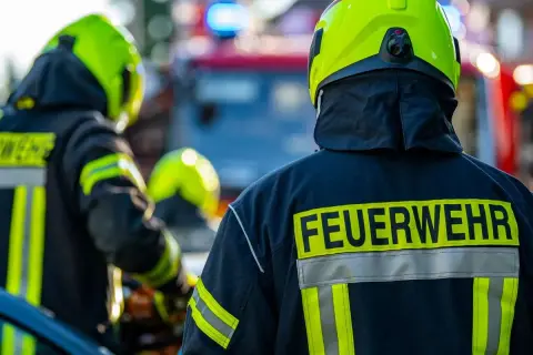 Feuerwehrleute in voller Montur, bereit für den Einsatz. Interessiert, wie viel verdient man als Feuerwehrmann netto?