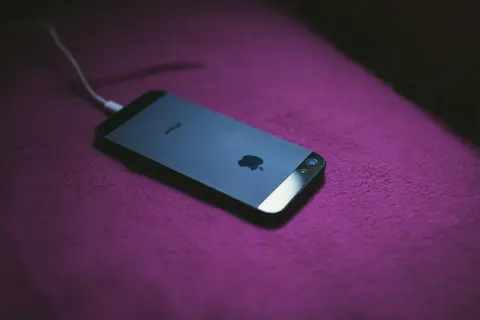 iPhone podłączony do ładowania. Dowiedz się, jak zmierzyć pojemność baterii, aby wiedzieć, jak długo telefon będzie działał.
