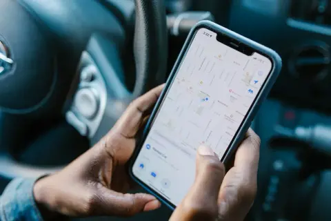 Dłonie trzymają telefon z mapą, szukając drogi. Aplikacja Zenly pomaga odnaleźć zaparkowany samochód.