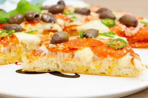 Pyszna pizza z patelni z pikantnym salami, oliwkami i papryczką jalapeno. Idealna na szybki obiad.