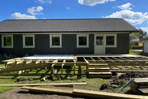 Grundarbete för att bygga veranda. Träkonstruktion och trappor på plats framför huset.